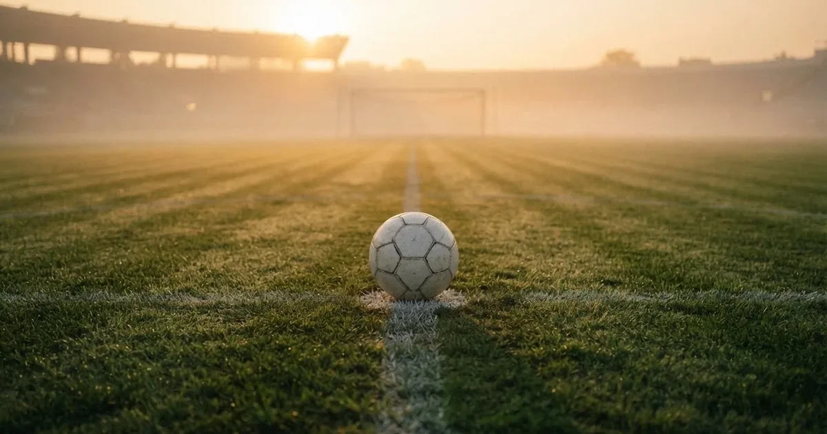 A ball on the centre spot of a grass pitch in morning light